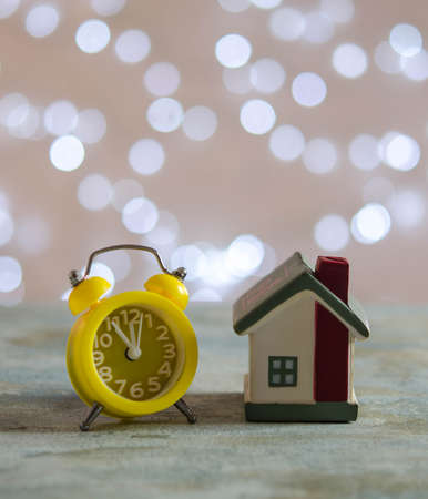 Small house and yellow alarm clock on the table. Christmas decorationsの写真素材