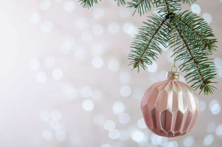 A pink ball hangs on a Christmas tree branch. Bokeh. Christmas decoration