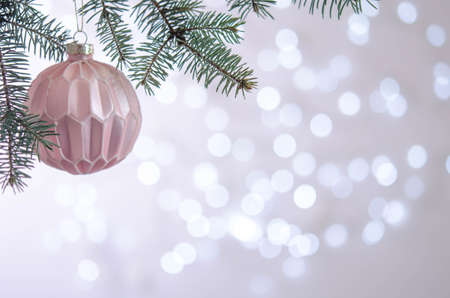 A pink ball hangs on a Christmas tree branch. Bokeh. Christmas decorationの写真素材