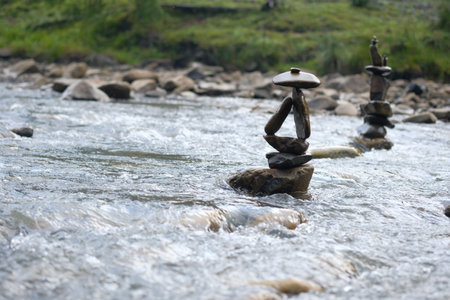 Two figures made of river stones in the middle of the stream. Riverbed, stones, creativity.の写真素材