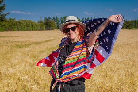 woman in a wheat field with a USA flag landscape full of colorsの写真素材