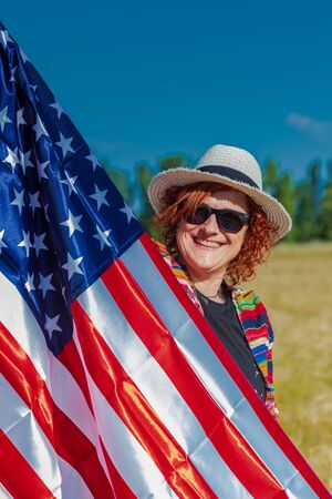 woman in a wheat field with a USA flag landscape full of colorsの写真素材