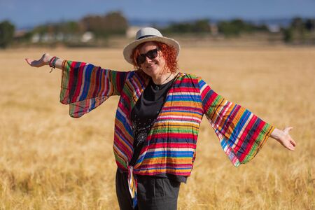 woman in a wheat field with a hat landscape full of colorsの写真素材