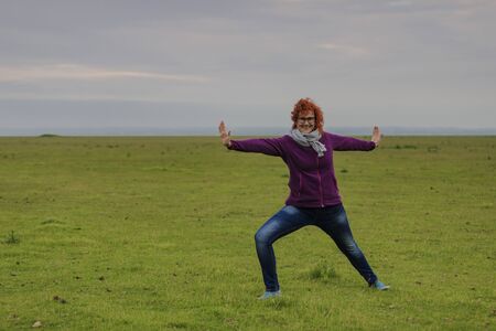 redhead woman practicing yoga warrior's position (Virabhadrasana)の写真素材