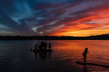 playing instruments on the lake sunset with incredible colorsの写真素材