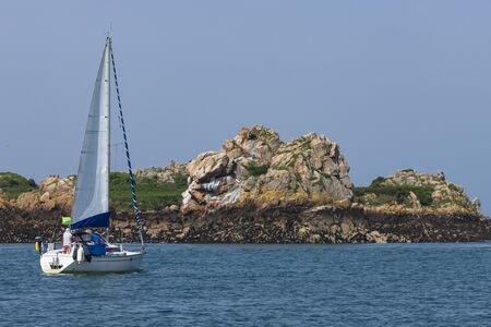 boat with sail deployed sailing on the island of Br? hatの写真素材