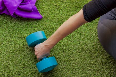 woman lifting a dumbbell with a purple towelの写真素材