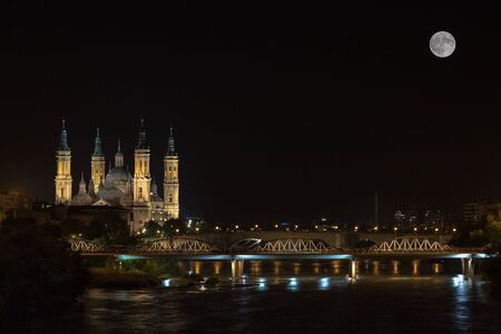 full moon next to the cathedral of our lady of the pilarの写真素材