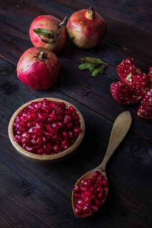 three pomegranate with bowl on real wooden table and wooden spoon wonderful colorsの写真素材