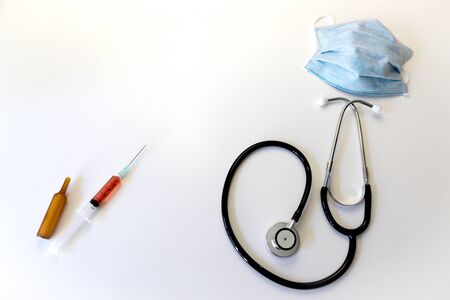 syringe, stethoscope mask on a table and white backgroundの写真素材