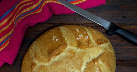 bread fresh from the oven on a dark wooden table with a colored clothの写真素材