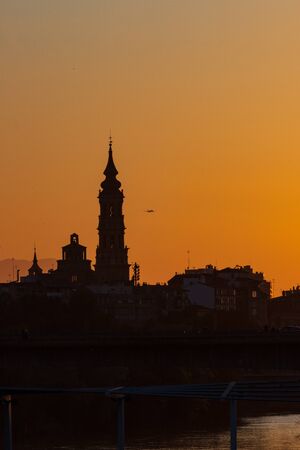 sunset in Zaragoza with the cathedral in the background and a plane taking offの写真素材
