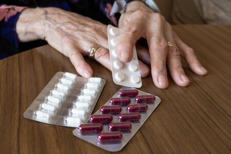 old woman preparing her pills with medical remote assistance button on the wristの写真素材