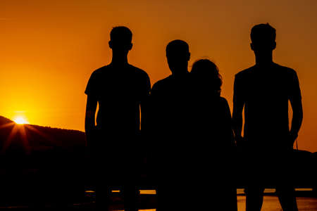 Silhouettes of a family of 4 members father, mother and two children. Backlightの写真素材