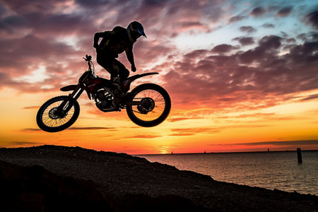 Silhouette of a motocross rider jumping on the beach at sunset generative AIの素材