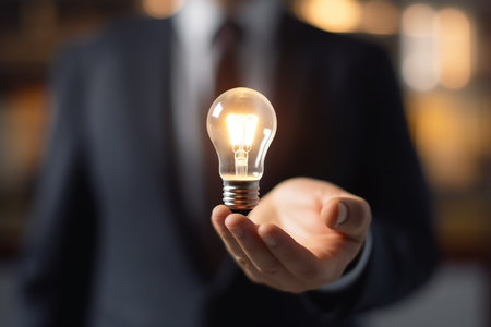 Businessman holding a glowing light bulb in his hand, concept of idea. generative AIの素材