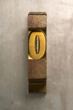 Brass / Gold colored letterpress piece on silver metal backgroundの写真素材