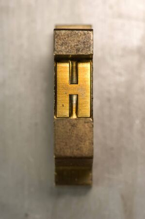 Brass / Gold colored letterpress piece on silver metal backgroundの写真素材