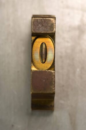 Brass / Gold colored letterpress piece on silver metal backgroundの写真素材
