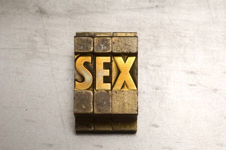 Brass / Gold colored letterpress piece on silver metal backgroundの写真素材