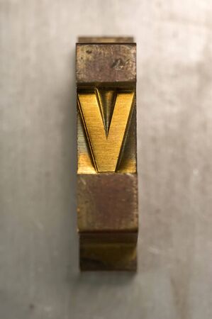 Brass / Gold colored letterpress piece on silver metal backgroundの写真素材