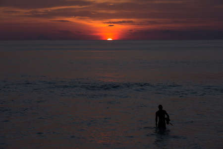 Silhouette of a swimmer during the golden sunset over the ocean on the beach