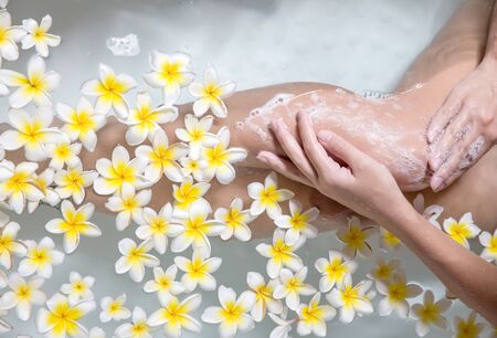Woman legs in bath tube with flowers spa relaxation body care therapy conceptの写真素材
