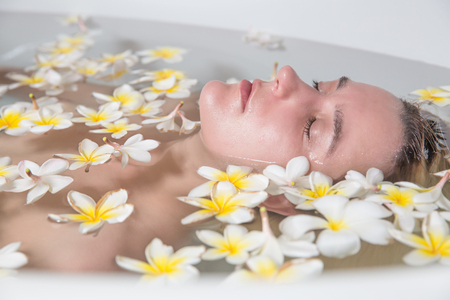 Beautiful young woman relaxing in bath with tropical flowers organic skin care luxury spa hotelの写真素材