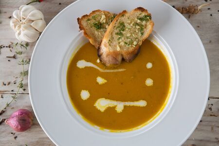 Pumpkin and carrot soup with crunchy bread and spyces on the sideの写真素材