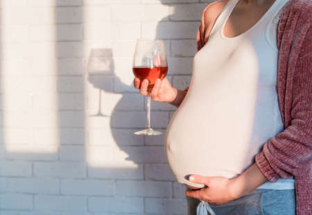 Unrecognized Pregnant woman with glass of red wine in handの写真素材