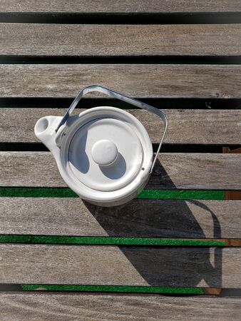 White tea pot with hearts on a table in a sunny day - tea timeの写真素材
