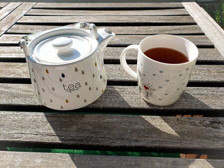 White tea pot with hearts on a table in a sunny day - tea timeの写真素材