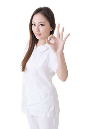 Smiling Asian nurse give an Okay sign, closeup woman portrait isolated on white background の写真素材