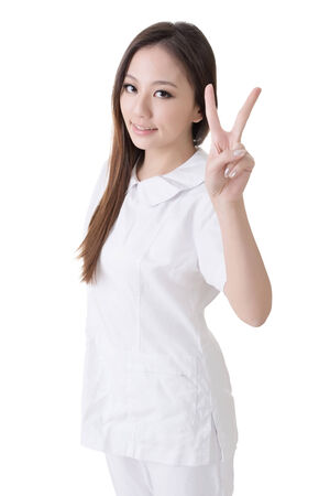 Smiling Asian nurse give an peace sign, closeup woman portrait isolated on white background の写真素材
