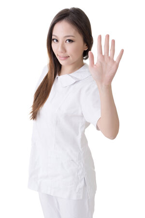 Smiling Asian nurse give a stop sign, closeup woman portrait isolated on white background の写真素材