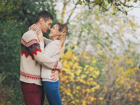 Young attractive couple in knitted sweaters having fun at sea shoreの写真素材