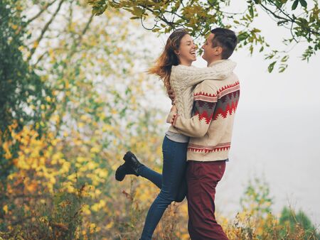 Young attractive couple in knitted sweaters having fun at sea shoreの写真素材