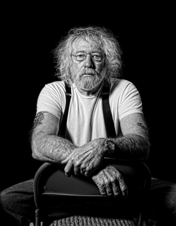 Serious tough old man with wild hair in monochrome isolated on blackの写真素材