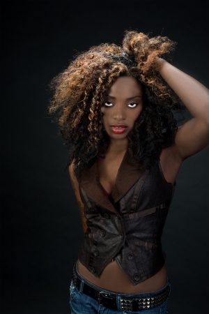 Sultry exotic African American woman with big hair and beautiful red lips against a dark backgroundの写真素材