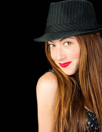 Beautiful young woman with hazel eyes and gorgeous long red hair wearing a pinstriped fedora smilingの写真素材