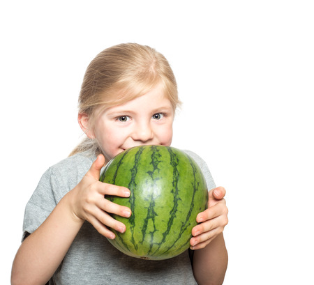 Happy smiling child with beautiful hazel eyes holding up a small watermelonの写真素材