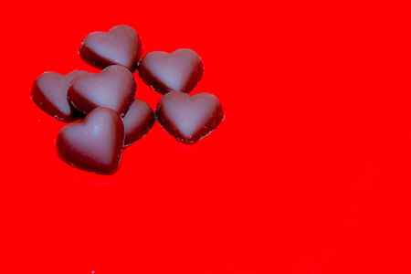 Chocolate hearts arranged on red background