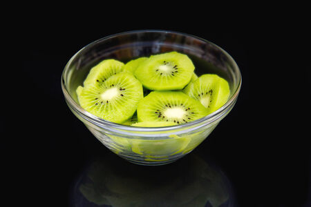 Slices of kiwi fruit on bowl on a black backgroundの写真素材