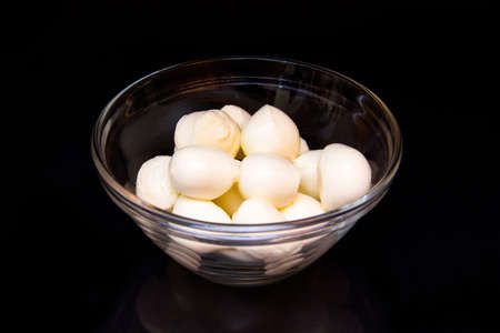 Small mozzarella in bowl on black backgroundの写真素材
