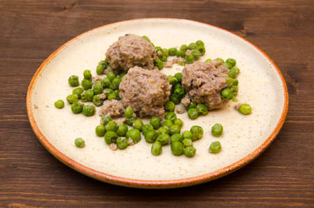 Meatballs with peas on the plate on wooden tableの写真素材