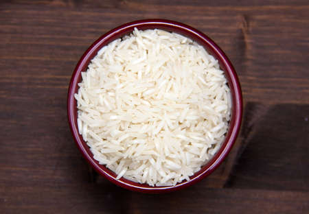 Bowl with uncooked rice on wooden table seen from aboveの写真素材