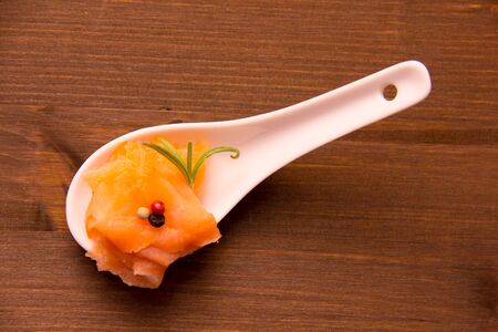Smoked salmon on spoon on wooden table seen from aboveの写真素材