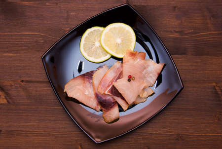 Smoked swordfish on black plate on wooden table topの写真素材