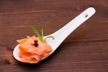 Smoked salmon on spoon on wooden tableの写真素材