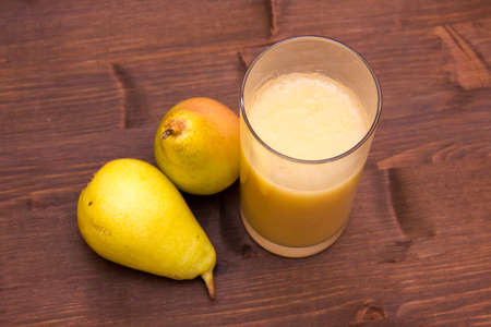 Glass with pear juice on wooden table seen from aboveの写真素材